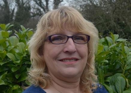 a woman wearing glasses and smiling at the camera